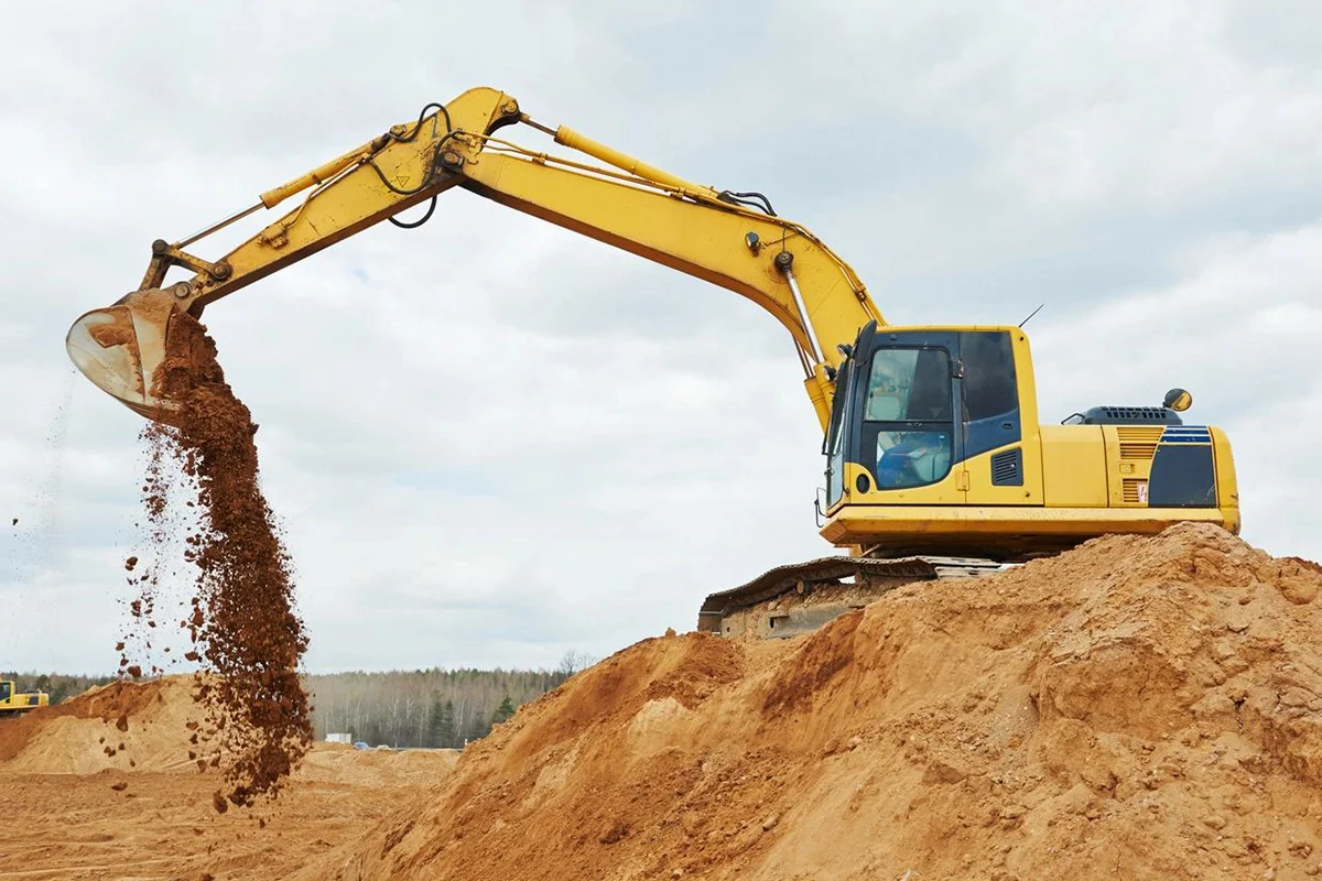 A yellow and black excavator is on the dirt