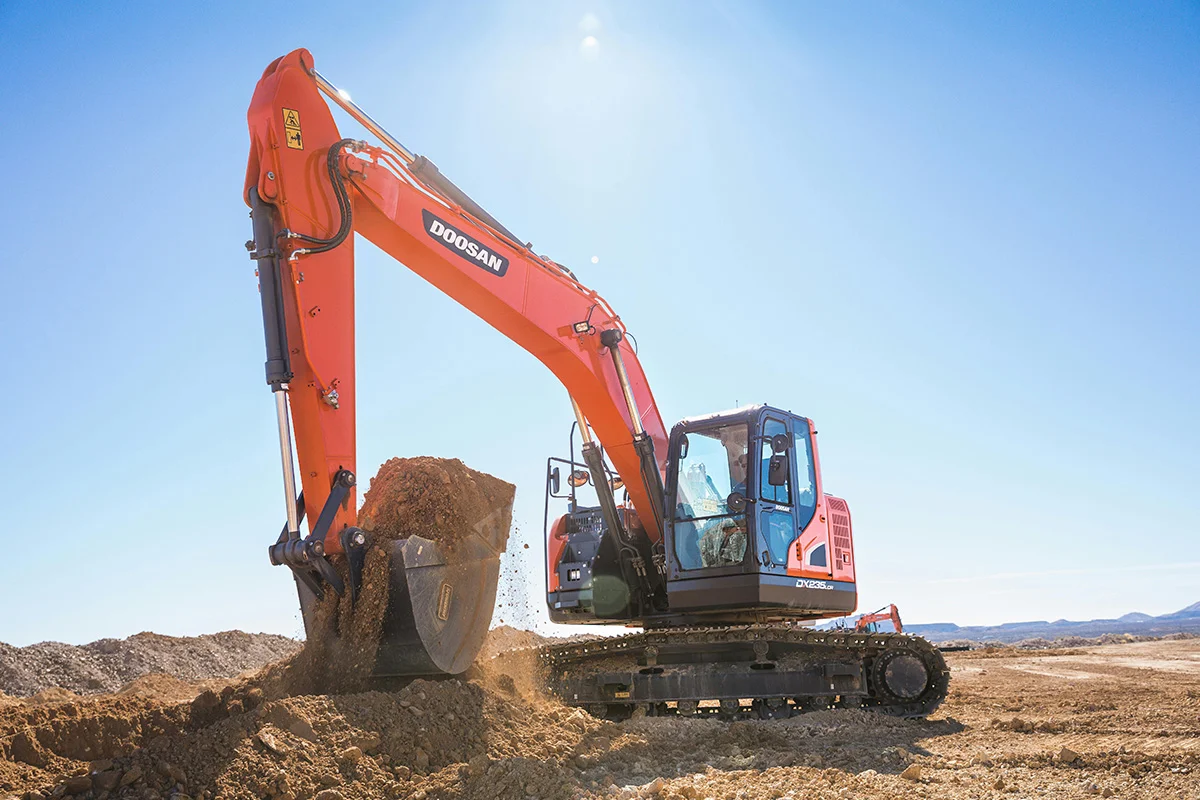 A large orange and black excavator on top of dirt.