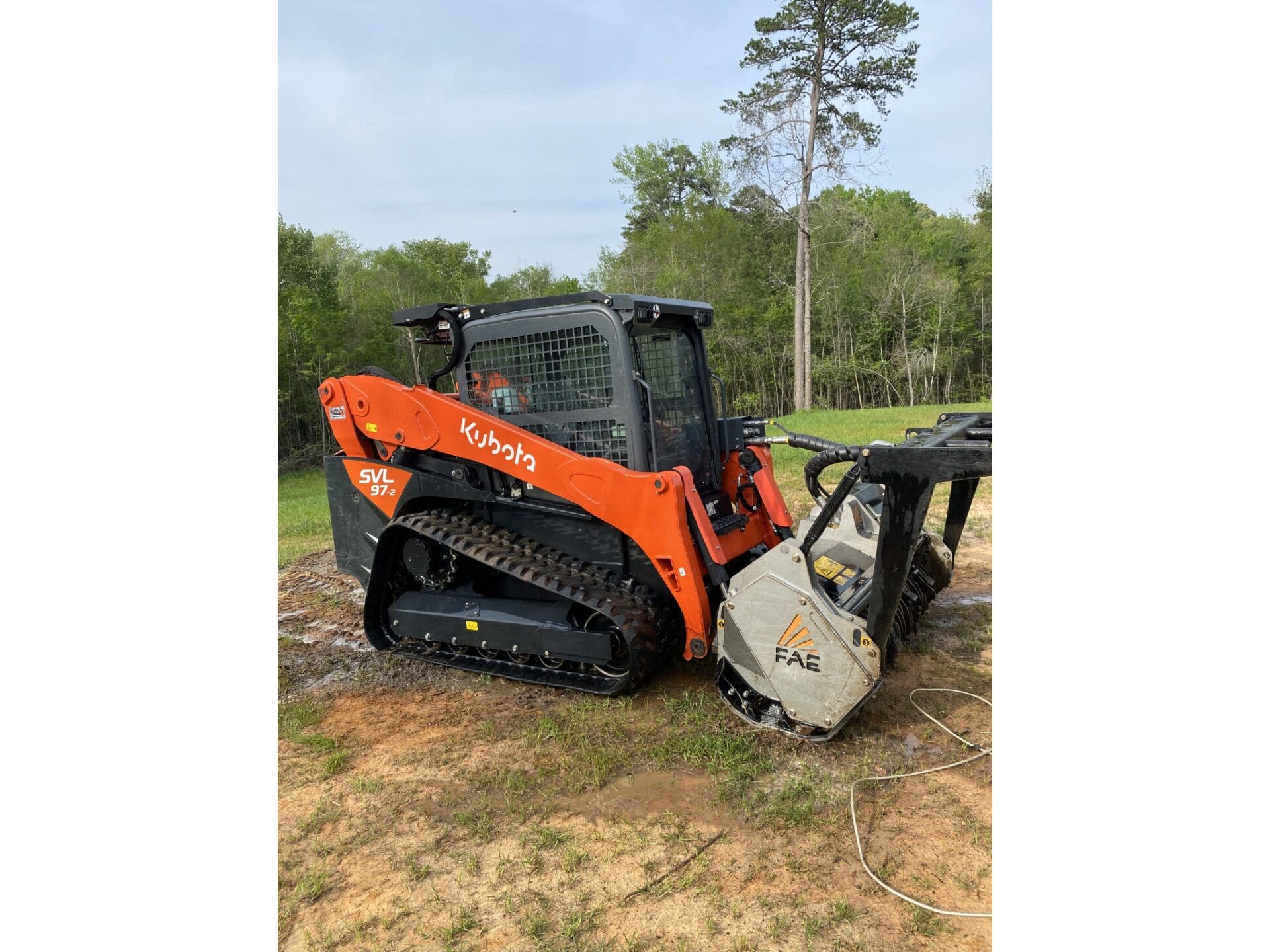 A small orange and black tractor is parked on the grass